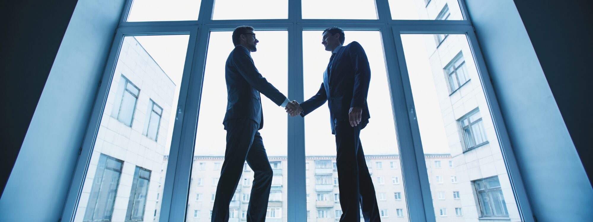 Two individuals in suits shaking hands